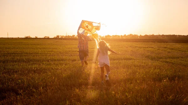 ガラスの中の大胆な父親は 空の凧に入れて娘と一緒にフィールドの周りを実行します 100万人の男が農村部の少女と遊ぶ 父の日に楽しい 暖かい幸せな家族の思い出 — ストック写真