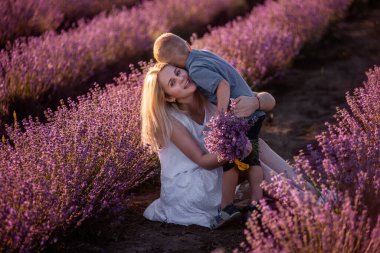 Küçük oğlu gün batımında annesine lavanta tarlasında parlak bir buket verir. Beyaz elbiseli genç bir kadın oğlanın hediyesine seviniyor. Alerji, seyahat, bekar ebeveyn kavramı. Tatil yaşam tarzı