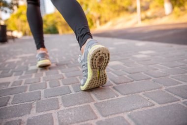 Maraton koşan bir sporcunun spor ayakkabılarına yakından bakın. Kadınların bacakları koşu yapmakla meşgul. İz ayakkabıları. Dişi bacakları hareket halinde. Uzayı kopyala Arkadan Sport Runner