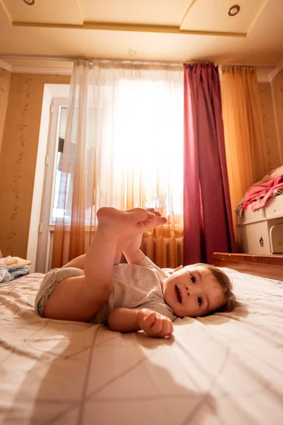 One Year Old Baby Bodysuit Lies Back Dangling Legs Bed — Stock Photo, Image