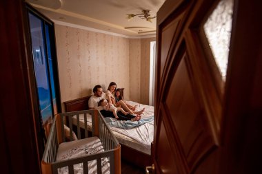 Sabahın köründe pencereden güzel bir ailenin uzun menzilli fotoğrafını çektim. Anneye, babaya, kıza, oğlana dokundum. Aile hafta sonu, evde rahatlama. Aile yatak odası manzarası