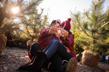 Kırmızı beyaz şeker kamışı, kareli gömlekli, yeşil Noel ağaçlarının yakınında örülmüş şapkalı, sevgi dolu çiftlerin uzanmış ellerinde tutuluyor. Mutlu erkek ve kadın öpüşür, güler. Boşluğu kopyala