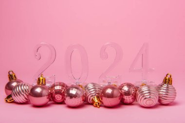 İzole edilmiş parlak pembe arka planda saydam sayılar 2024 ve noel ağacı gibi parlak toplar. Yılbaşı kartı. Metin için şablon. Gelecek yılın sembolü, planlama, finans. Boşluğu kopyala