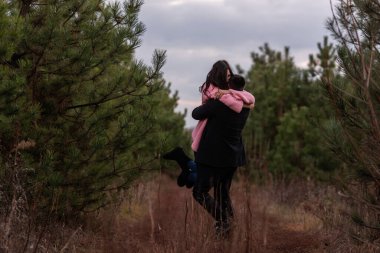Mutlu çift yoldaki kozalaklı ormanda dönüyor. Genç adam pembe kazaklı kıvırcık saçlı kadına sıkıca sarılıyor. Kış nişanı, sonbahar düğünü. Evlenme teklifi. Yaşam tarzı, kırsal kesim. Boşluğu kopyala