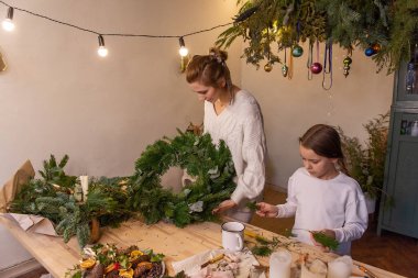 Genç anne ve küçük kızı birlikte ladin ve okaliptüs dallarından Noel çelengi yapıyorlar. Bekar anne, kızlara yeni yıl dekorasyonunun nasıl yapılacağını öğretiyor. Tatil için aile ortamı