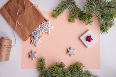 Şeftalili tüy yumağında Noel için gümüş zencefilli kurabiye şeklinde el işi çanta var. Yeşil köknar dalları, sicim, kırmızı fiyonklu beyaz hediye kutusu olan durgun yaşamın en üst görüntüsü
