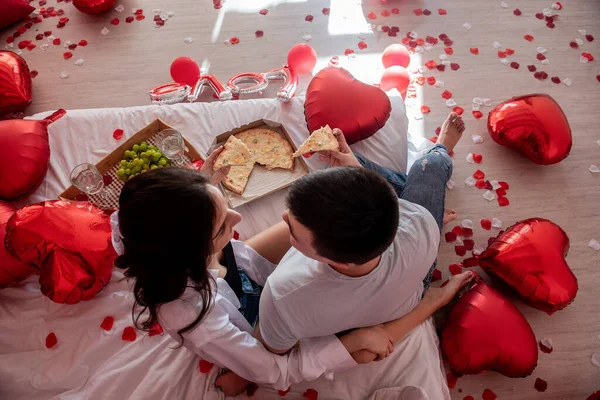 看到一对年轻夫妇互相喂食 享受着从外卖箱带来的披萨 喝着香槟 喝着绿葡萄 男人和女人在床上共度欢乐 亲密的时光 情人节 — 图库照片