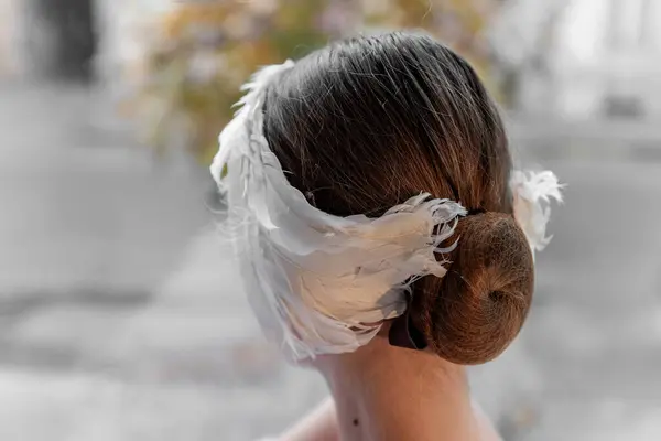 特写的独特的白色羽毛头饰头饰环绕着芭蕾舞女郎的发髻 融合了传统与现代风格 芭蕾发型 — 图库照片