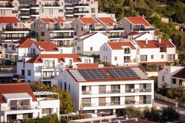 Bazıları güneş panelleri ile donatılmış kırmızı kiremitli çatıları olan modern konut binaları kümesi. Kentsel konutlarda sürdürülebilir yaşam ve çevre dostu enerji çözümleri sunar. Hırvatistan