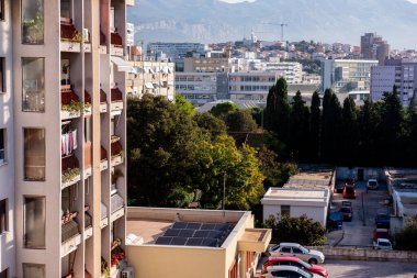 Çatıda güneş panelleri olan, yoğun yeşilliklerle çevrili, kentsel sürdürülebilirlik ve doğanın birlikteliğini temsil eden meskun dairelerin yakın görüntüsü.