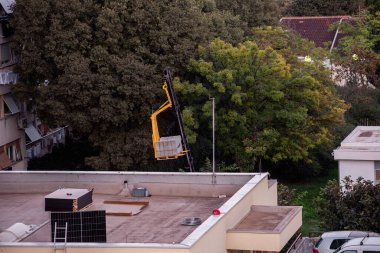 İnşaat vinci, yenilenebilir enerji kurulumu ve kentsel altyapı gelişimini gösteren güneş panelleri olan bir çatıda beton bir blok konumunda..
