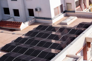 Düz bir çatıya kurulmuş güneş panelleri kentsel yerleşim ortamında yenilenebilir enerji için güneş ışığını yakalıyor..
