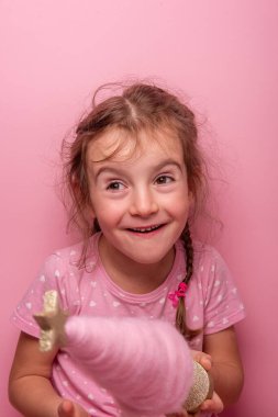 Pembe elbiseli gülümseyen kız pembe bir arka planda parlak bir yıldızla süslenmiş kaprisli pembe bir ağacı tutuyor. Eğlenceli, neşeli ve neşeli bir ruh hali..