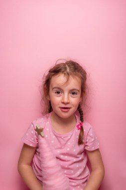 Pembe elbiseli gülümseyen kız pembe bir arka planda parlak bir yıldızla süslenmiş kaprisli pembe bir ağacı tutuyor. Eğlenceli, neşeli ve neşeli bir ruh hali..