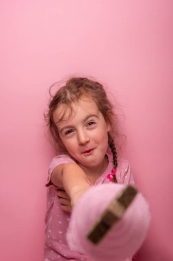 Pembe elbiseli gülümseyen kız pembe bir arka planda parlak bir yıldızla süslenmiş kaprisli pembe bir ağacı tutuyor. Eğlenceli, neşeli ve neşeli bir ruh hali..