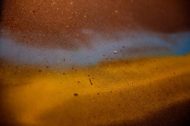 Mavi ve sarı sprey boyaların birbirine karıştığı desenli bir yüzeye yakın çekim, dağınık parçacıklarla soyut ve sanatsal bir etki yaratıyor. Ukrayna bayrağı