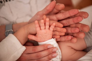 Farklı nesillerden gelen çoklu eller aile birliği ve sevgiyi sembolize ediyor. Yetişkin ve bebek elleri dokunaklı bir bağ ve destek sahnesi yaratır.