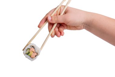 Somon, avokado ve salatalıklı bir suşi rulosunu beyaz arka planda tutmak için ahşap çubuklar kullanan bir elin yakın çekimi..
