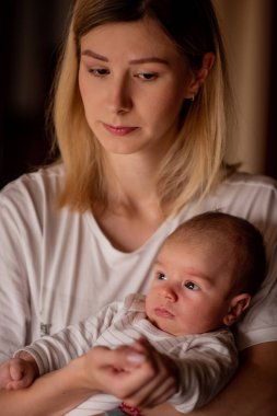 Anne, yeni doğmuş bebeğini nazikçe kucağına alıp, sıcaklığını ve bakımını iletiyor. Samimi an, anne olmanın besleyici yönünü vurgulayarak, aralarındaki bağı ve sevgiyi yakalar.