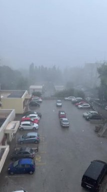 Hırvatistan 'ın Split kentinde yağışlı yağmurlu ve ıssız park yeri, sisli, gri atmosfer ve park halindeki araçları çevreleyen su kaplı kentsel manzaralı kasırga sonrasını gözler önüne serdi.