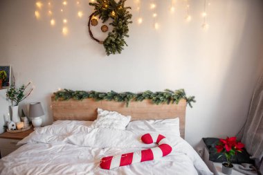 Noel yatak odasının içinde şeker kamışı yastığı, köknar dalları, peri ışıkları ve Noel için şenlikli bir ortam yaratıyor.