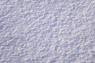 Natural winter texture background. Hilly snow surface close-up in sunny day. Copy space, top view.