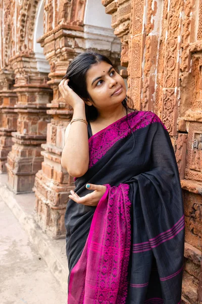 A pretty Indian woman in saree near a terracotta temple of West Bengal