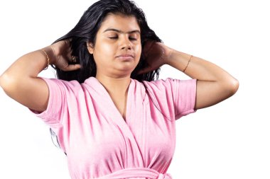 Güzel bir Hintli kadın siyah saçlarına saç yağı sürüyor ve beyaz arka planda gülümsüyor.