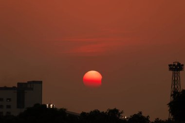 Güneş ufuk yakınlarındaki turuncu gökyüzünde batarken kısmi güneş tutulması
