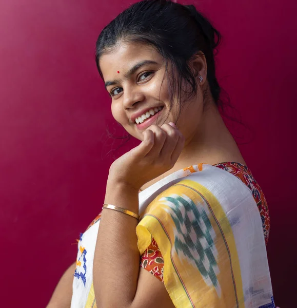A pretty Indian woman in saree smiling on a colored background