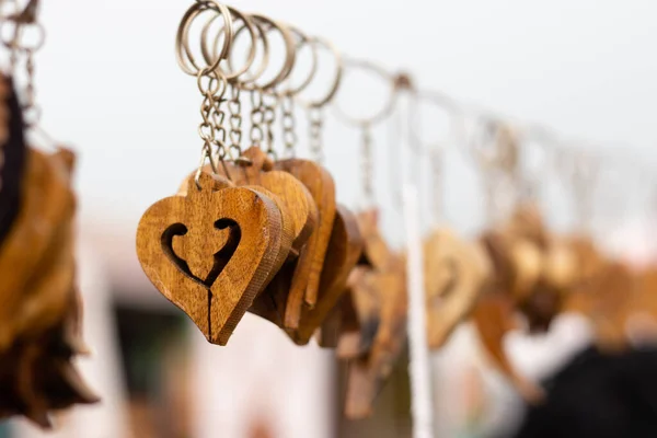 Colorful hand made love shaped wooden key rings hanging on sale at roadside market stall