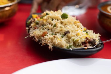 A plate of mixed fried rice - a chinese Indian food served on red table
