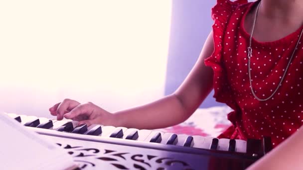 一名印度女童手弹奏和声 有选择地侧重于白人背景 — 图库视频影像
