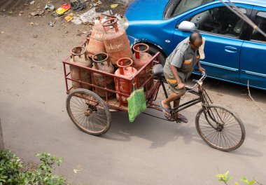 Howrah, Batı Bengal, Hindistan - 20 Mart 2023: Indane LPG silindiri taşıyan Hintli bir kurye