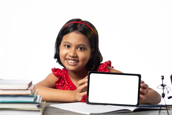 一个漂亮的印度女孩在白底的书桌上学习和展示空白的平板电脑 — 图库照片