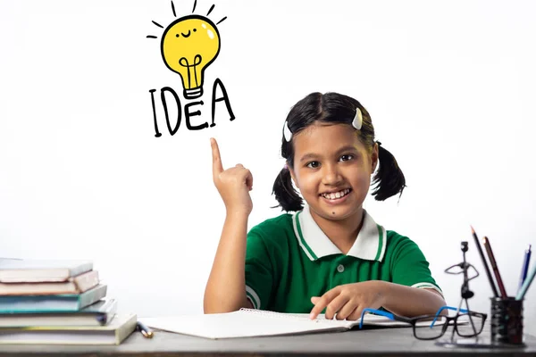 一个漂亮的印度女孩在学习桌旁学习 笑脸向上看去 白色背景上的想法灯泡标志 — 图库照片