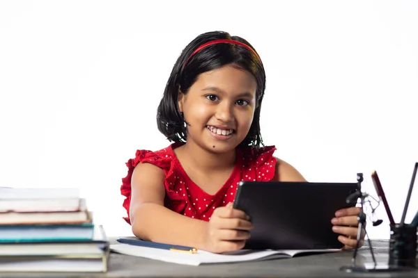 かなり美しいですインドの女の子勉強とともにタブレットで勉強テーブル上の白い背景 — ストック写真
