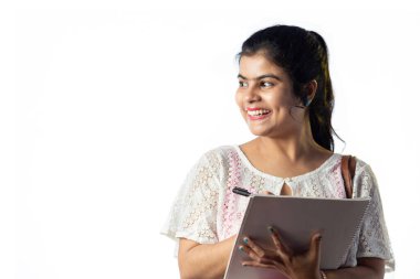 Mutlu ve güzel bir Hintli kızın portresi. Not alıyor ve beyaz arka plana yan bakıyor.