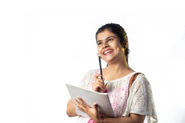 Not alırken düşünen ve beyaz arka planda yukarıya bakan güzel bir Hintli kız.