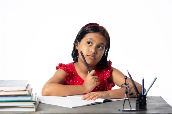 一个漂亮的印度女孩 带着白色背景的书 学习着 抬头看着书桌 — 图库照片