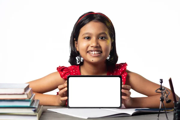 一个漂亮的印度女孩在白底的书桌上学习和展示空白的平板电脑 — 图库照片