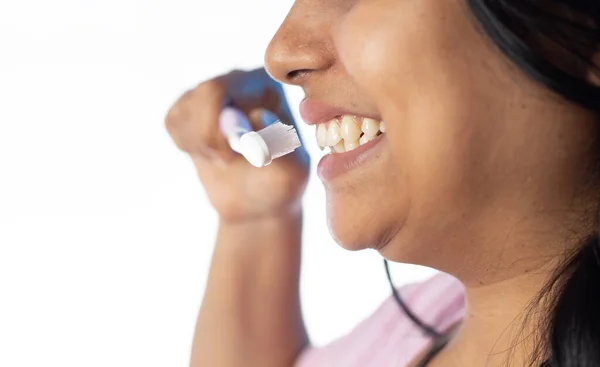 Close up side face of an Indian woman female girl brushing teeth on white background