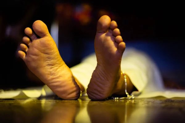 Feet of an Indian or Asian female dead body lying on floor in a dark room