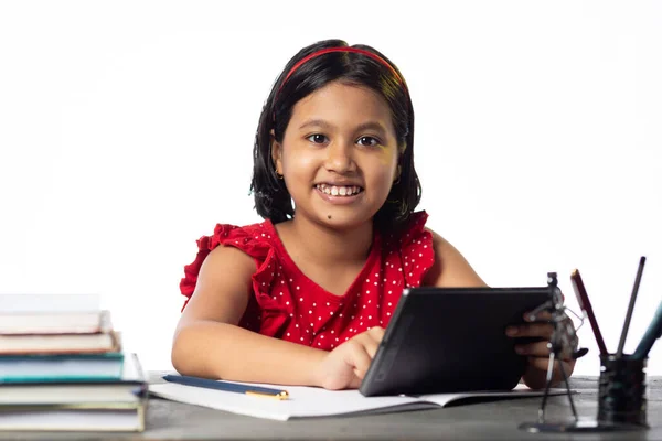かなり美しいですインドの女の子勉強とともにタブレットで勉強テーブル上の白い背景 — ストック写真