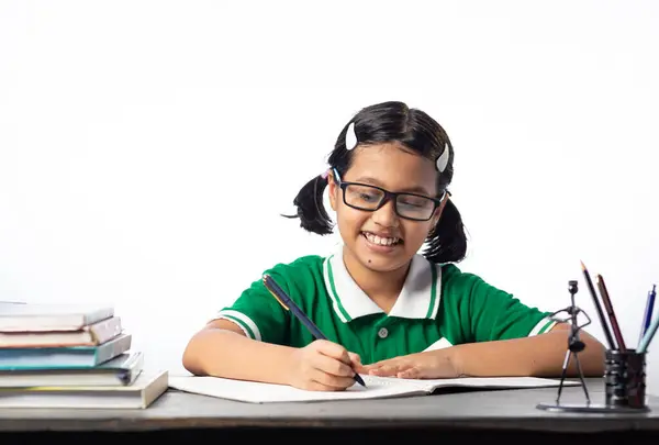 一个漂亮的印度女学生 戴着眼镜 在白底的课桌上读书写字 — 图库照片