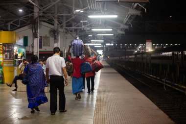 Dhanbad, Jharkhand, Hindistan - 26 Ekim 2023: Hamal ya da işçi bir ailenin bagajını gece Hint tren peronunda taşıyordu.