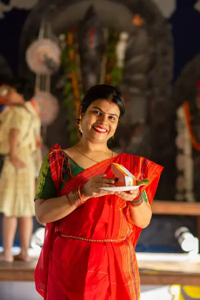 stock image A beautiful woman in traditional dress red saree with prayer plate and smiling face during last day of Durga Puja