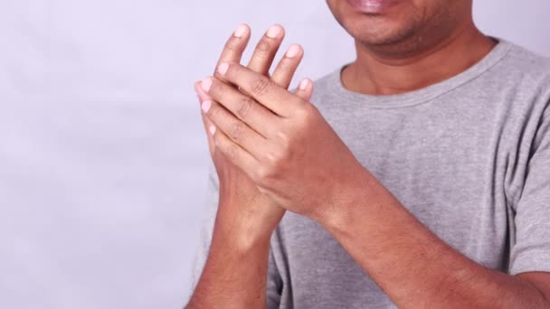 白い背景に痛みを伴う表情を示す関節痛のために手首と肘を保持するインド人男性 — ストック動画