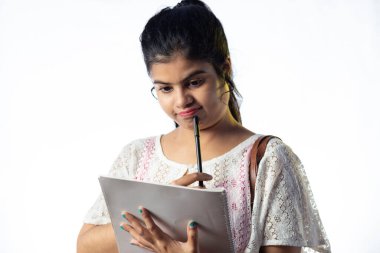 Genç ve güzel bir Hintli kız beyaz arka plan hakkında düşünüyor ve not alıyor.