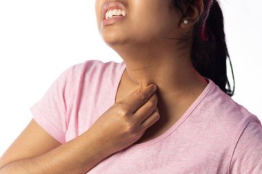 Beyaz arka planda acı dolu bir ifade gösteren boğazını tutan Hintli bir kadın.